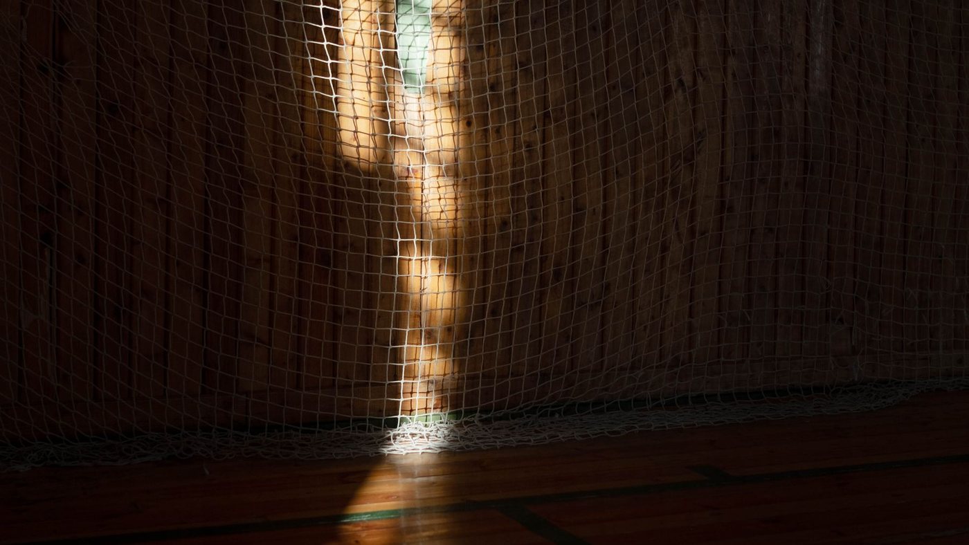 Um feixe de luz atravessando a rede de um ginasio escuro